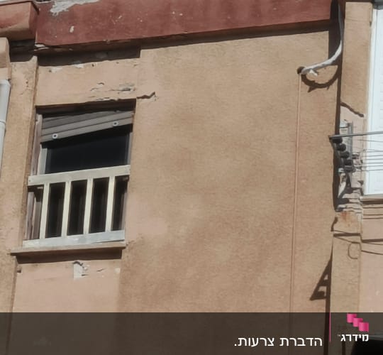 קיר חיצוני עם חלון קטן וצינור חשוף